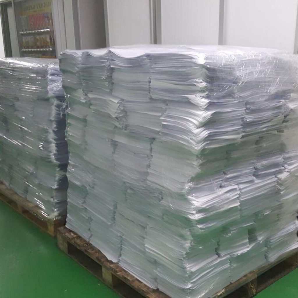 Stacked white and coloured office documents wrapped on pallets prepared for recycling in Singapore.
