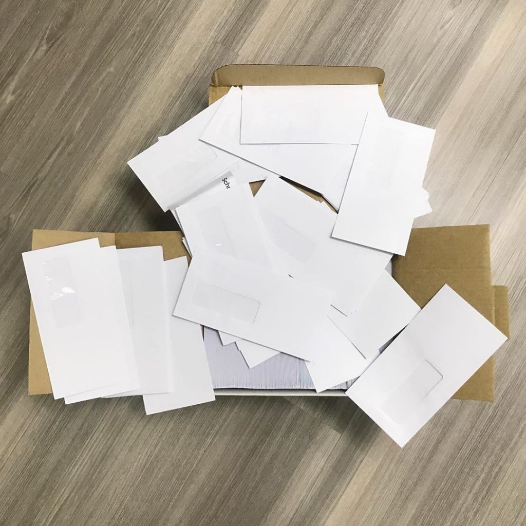 Collected white paper envelopes with plastic windows prepared for recycling in Singapore.