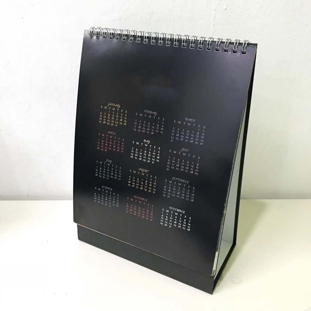 Used table calendars with metal wire binders showing proper separation for recycling in Singapore.